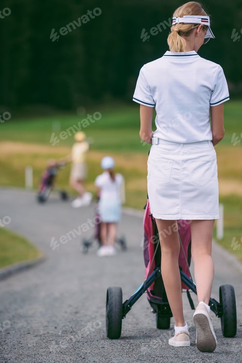 Preview: selective focus of female golf player in cap and white polo with golf gear at golf course