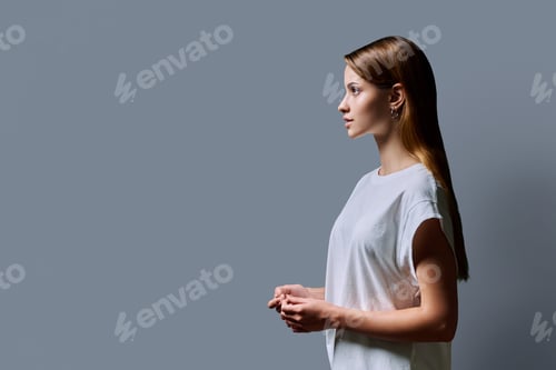 Preview: Profile portrait of young teenage girl, gray studio copy space background