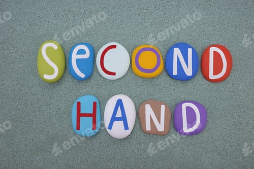 Preview: Second hand, creative logo composed with multi colored stone letters over green sand