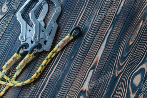 Preview: Isolated photo of climbing equipment. Part of carabiner lying on the wooden table