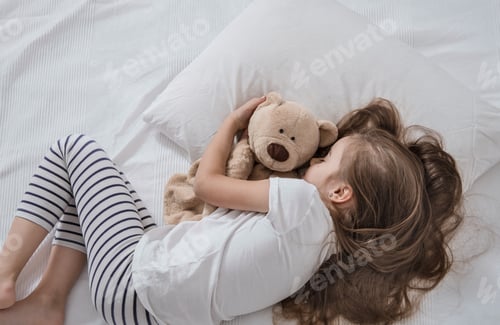 Preview: Cute little girl in bed with soft toy.