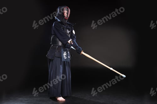 Preview: Full length view of kendo fighter in armor practicing with bamboo sword on black