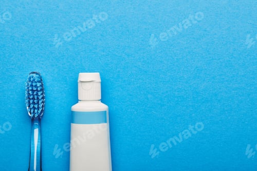 Preview: top view of toothbrush and toothpaste arranged on blue backdrop, dentistry concept