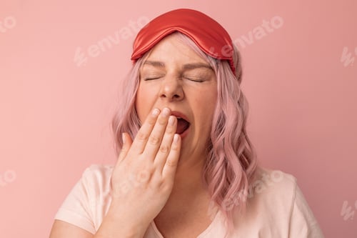 Preview: woman in sleepwear and mask covering her mouth while yawning relax at home