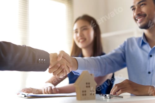 Preview: Young Asian couple making contract with house sale agency shaking hand with female agent.