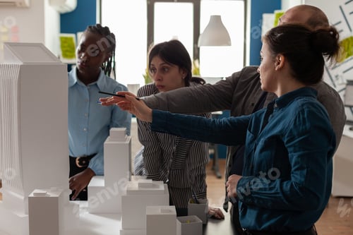 Preview: Team of professional architects brainstorming ideeas pointing at real estate construction model