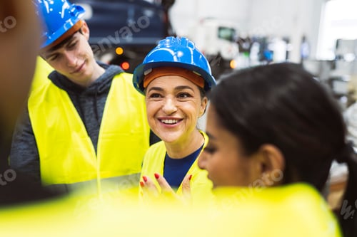 Preview: smiling mature woman worker in a robotics factory talking to her colleagues