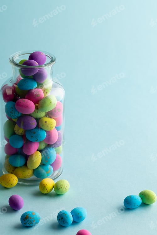 Preview: Image of multi coloured easter eggs in clear jar with copy space on blue background