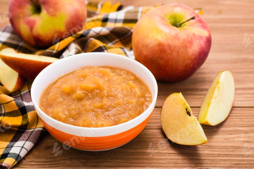 Preview: Apple puree in a bowl and apples on a wooden table