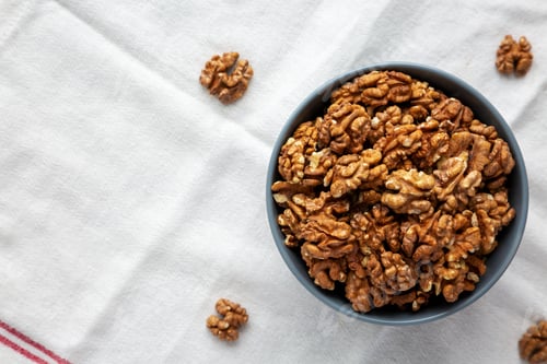 Preview: Raw Organic Walnuts in a Bowl, top view. Flat lay, overhead, from above.