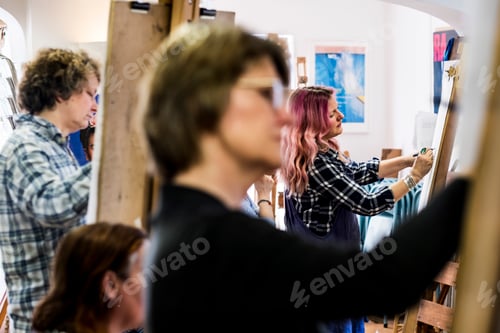 Preview: Close up of a woman standing at an easel, drawing.