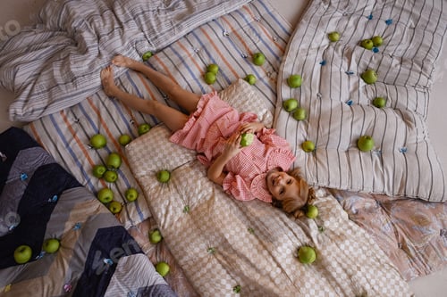 Preview: Little girl lying on mattresses with green apples, top view, princess and the pea concept