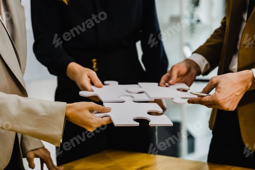 Preview: Concept of teamwork and partnership. Hands join puzzle pieces in the office