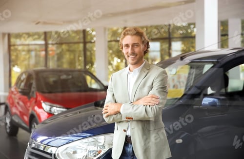 Preview: Young man near new car in modern auto dealership