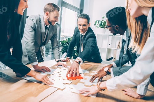 Preview: multiethnic businesspeople assembling puzzle together in conference hall