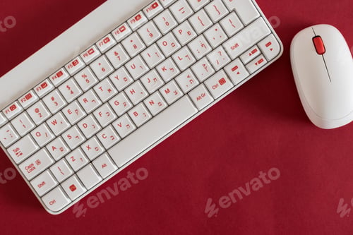Preview: Closeup shot of a white keyboard and mouse isolated on a red background