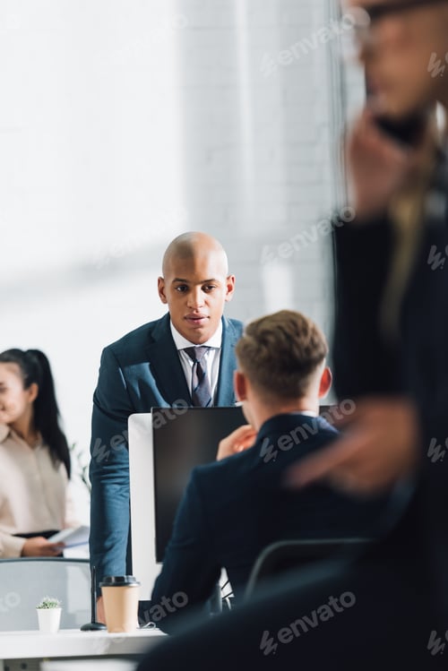 Preview: serious young african american businessman talking with colleague in office