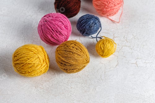 Preview: Balls of yarn in different colors with knitting needles.