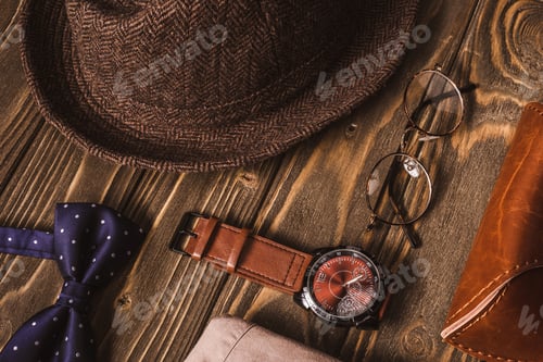 Preview: close up view of arrangement of masculine accessroies on wooden tabletop