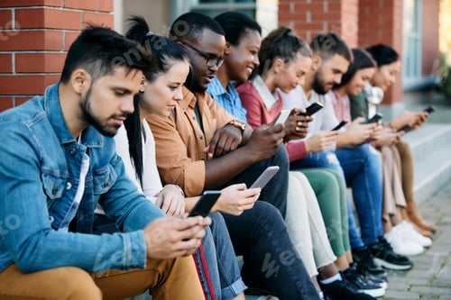 Preview: Young black student and his friends using mobile phones while sitting outdoors at campus.
