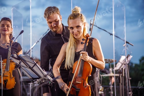 Preview: Beautiful woman violin player playing in orchestra outdoors