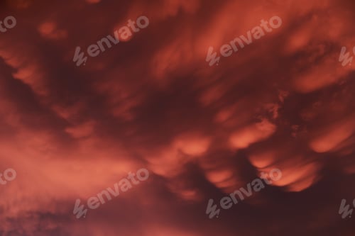 Preview: Dramatic sunset landscape with puffy clouds lit by orange setting sun and blue sky.