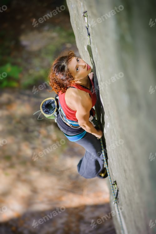 Preview: Beautiful woman climber climbing steep rock with rope