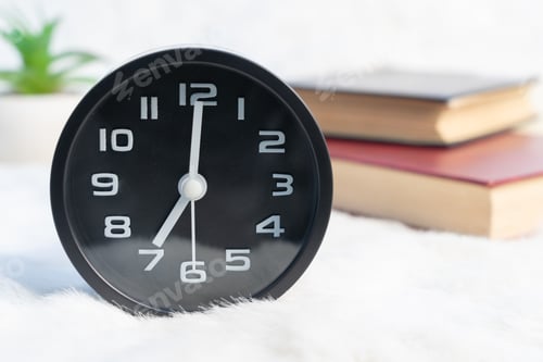 Preview: Black alarm clock and book stacked on table