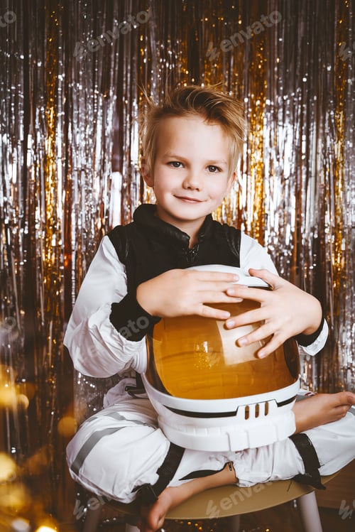 Preview: Child in fancy dress of astronaut pilot costume having fun at masquerade party in festive background