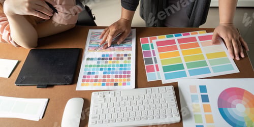 Preview: Graphic design team analyzing color palettes and materials in a collaborative workspace.