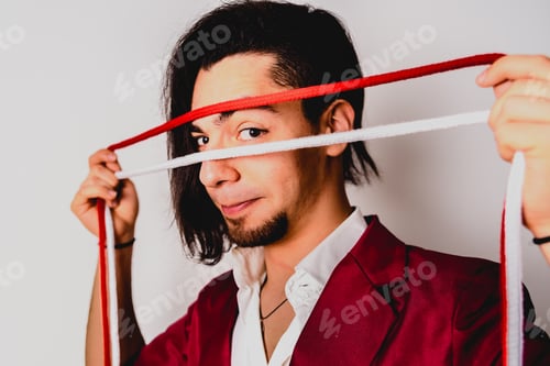 Preview: Portrait of young magician handling ropes and bandanas to do magic tricks, isolated on white.
