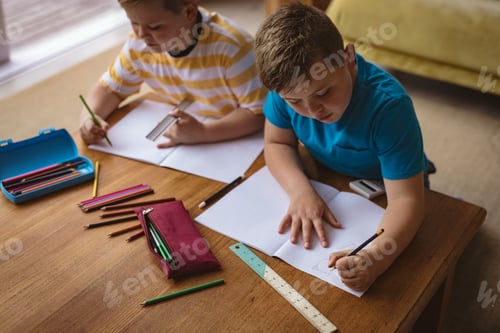Preview: Two caucasian boys drawing in their books sitting in the living room at home