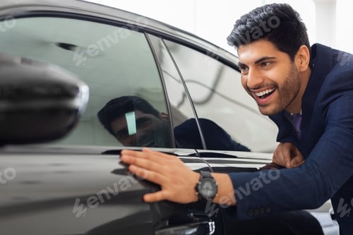 Preview: Excited middle-eastern businessman touching brand new car