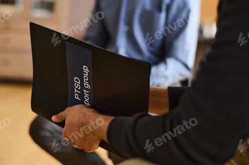 Preview: Black plastic folder in hands of young man with post traumatic syndrome