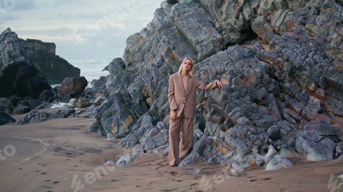 Preview: Glamour girl modeling beach leaning ocean rocks. Sexy blonde in elegant suit