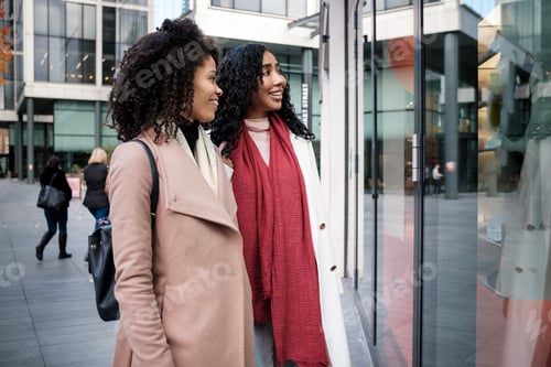Preview: Two female friends looking at retail display outdoors.