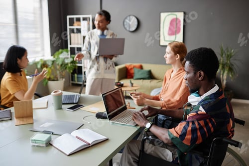 Preview: Young Black man with disability using laptop in business meeting
