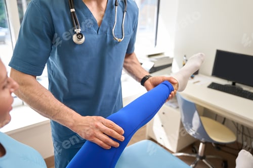 Preview: Rehabilitation specialist working with patient leg, straightening and massaging