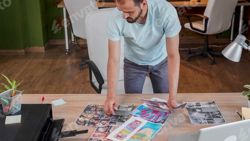 Preview: Young designer who looks over some printed pictures