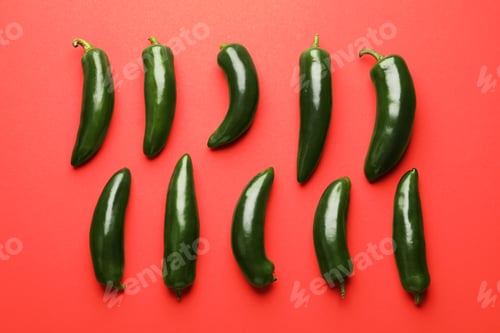 Preview: Green jalapeno peppers on red background, flat lay