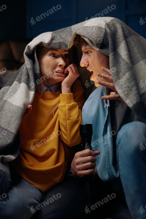 Preview: Man tells his girlfriend a scary story using a flashlight and covered with a blanket