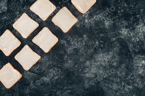 Preview: top view of fresh tasty toasts with butter on black slate board
