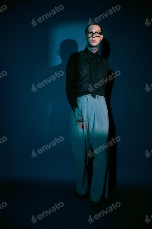 Preview: Stylish young man in a trendy outfit standing confidently against a vivid blue backdrop