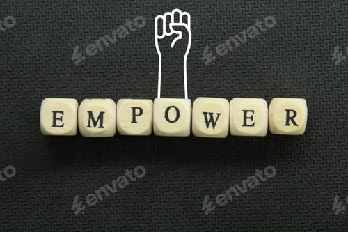 Preview: the word empower on a wooden cube with hands up