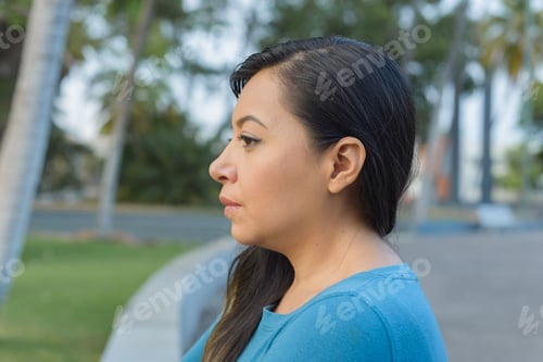Preview: Woman sitting in a public park with her arms crossed in a worried, thoughtful attitude.