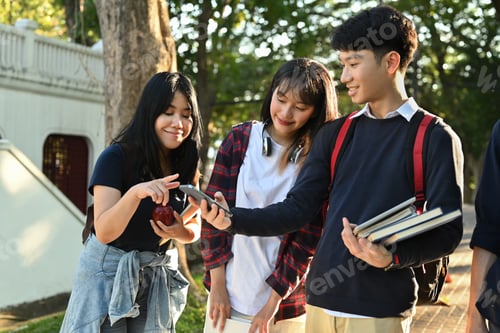 Preview: Group of asian students using mobile phone while walking together outdoors at university campus.