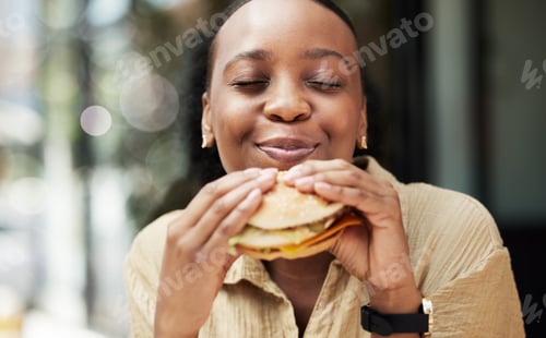 Preview: Restaurant, fast food and black woman eating a burger in an outdoor cafe as a lunch meal craving de