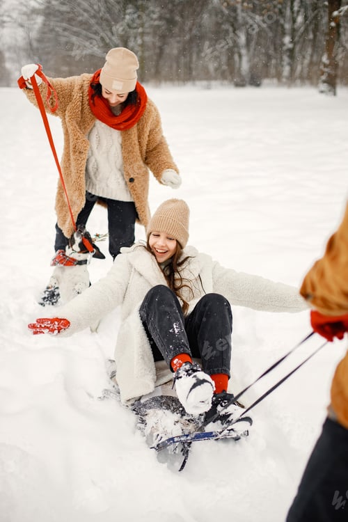 Preview: Teen siblings, their mother and black dog riding a sled at winter park