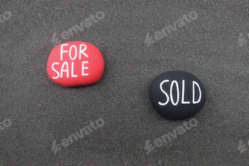 Preview: For Sale, Sold text carved on stones over black volcanic sand