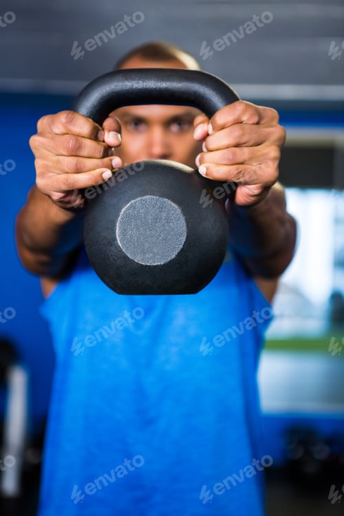 Preview: Man Covering Face With Kettlebell While Exercising In Gym